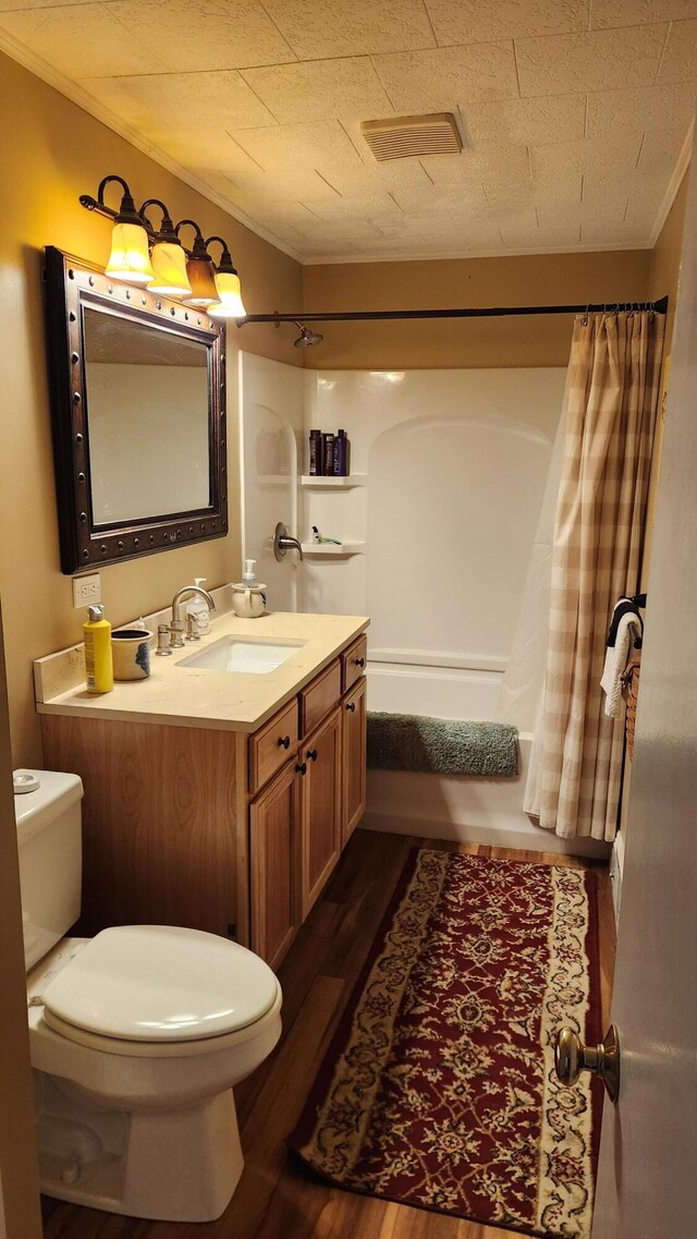 full bathroom with shower / bath combo, toilet, ornamental molding, wood finished floors, and vanity