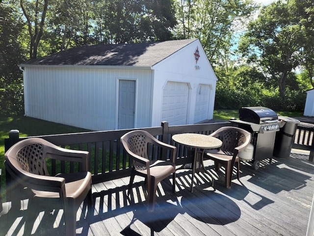 deck with a grill, an outdoor structure, and a detached garage