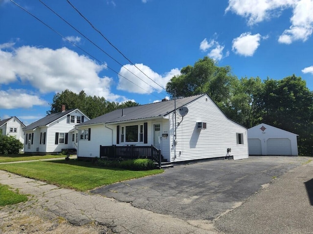 view of front facade with a garage, an outbuilding, metal roof, and a front yard