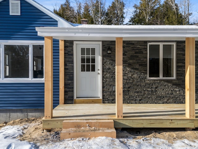 snow covered property entrance with a wooden deck