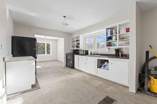 kitchen with sink, white cabinetry, black appliances, and hanging light fixtures