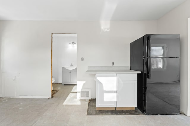 kitchen with black refrigerator and white cabinetry