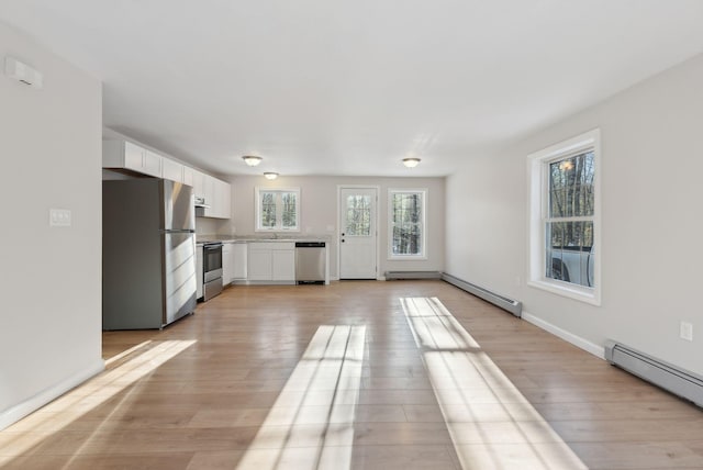 unfurnished living room with baseboard heating and light wood-type flooring