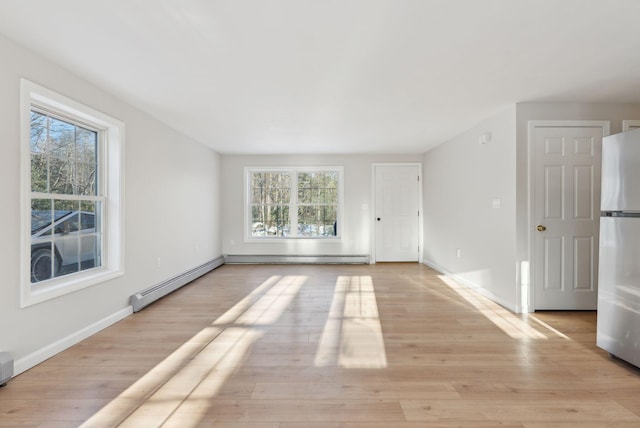 spare room featuring baseboard heating and light hardwood / wood-style flooring