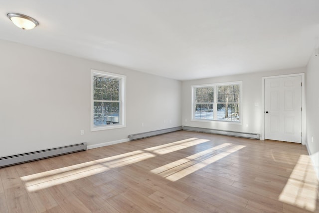 spare room featuring a baseboard heating unit and light hardwood / wood-style flooring