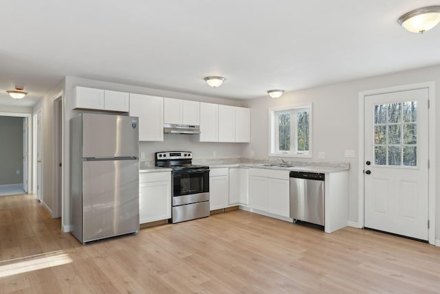 kitchen with appliances with stainless steel finishes, light hardwood / wood-style flooring, and white cabinets