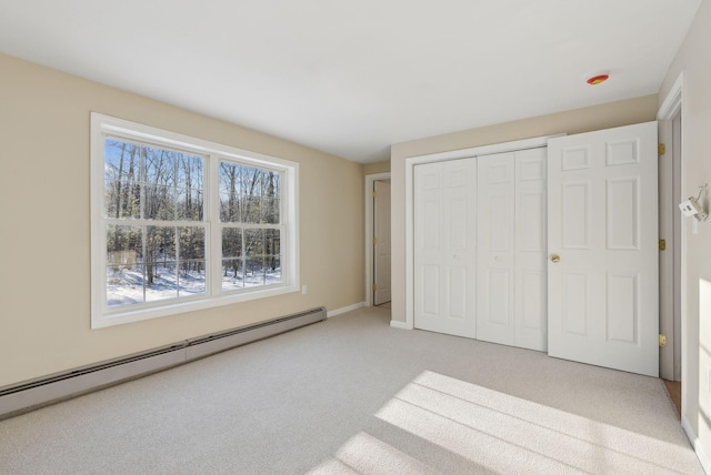 unfurnished bedroom featuring a closet, carpet flooring, and a baseboard heating unit