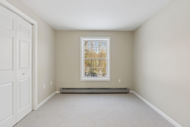 unfurnished bedroom featuring a closet, baseboard heating, and light colored carpet