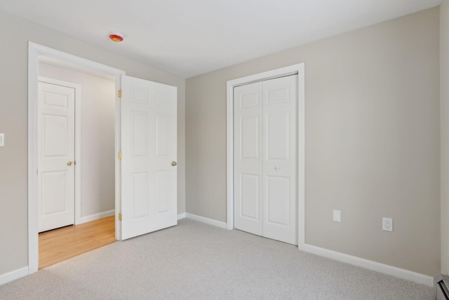 unfurnished bedroom featuring a closet, carpet, and a baseboard heating unit