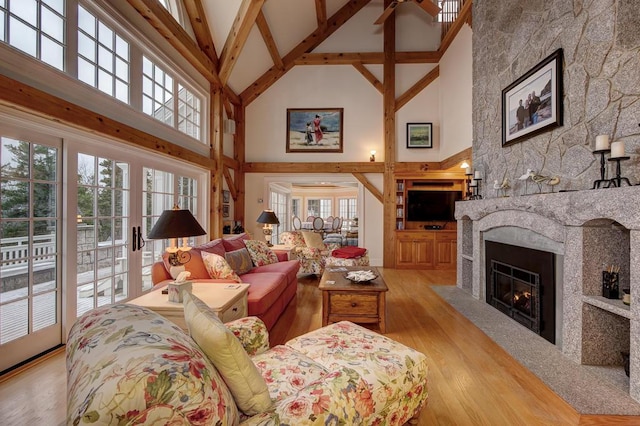 living room with a fireplace, beam ceiling, light hardwood / wood-style flooring, and high vaulted ceiling