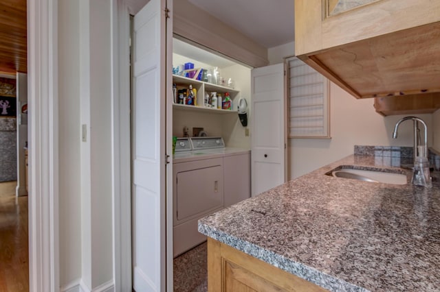 kitchen featuring light brown cabinetry, washing machine and dryer, and sink