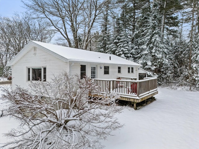 snow covered back of property with a deck