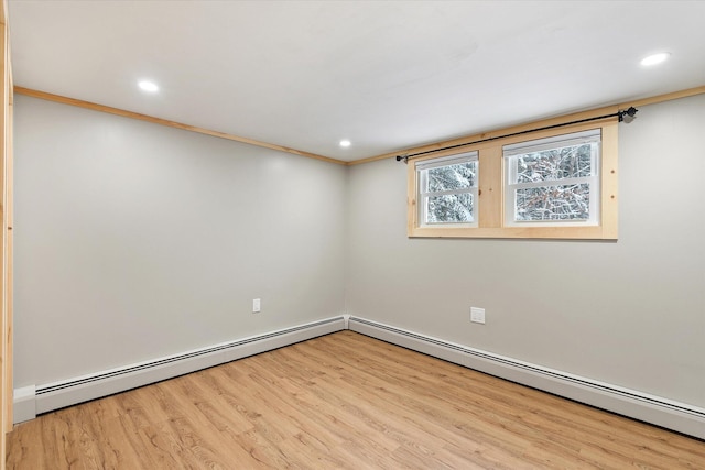 spare room with light hardwood / wood-style floors, baseboard heating, and crown molding