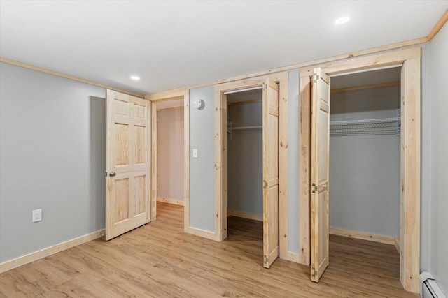 unfurnished bedroom with light hardwood / wood-style floors and a baseboard heating unit