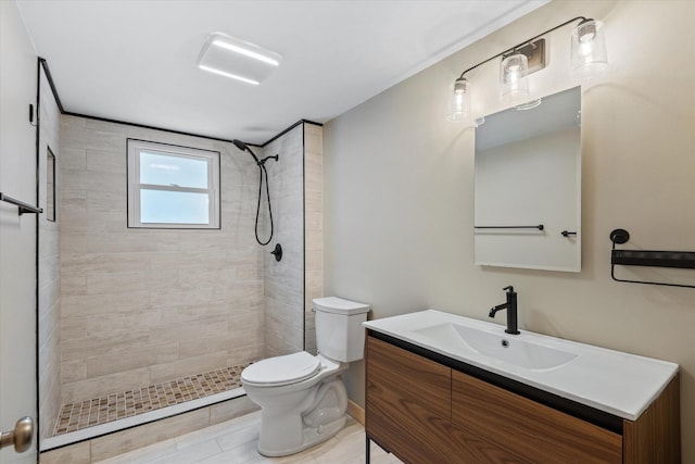 bathroom featuring tile patterned flooring, a tile shower, vanity, and toilet