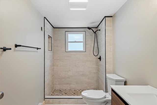 bathroom featuring a tile shower, tile patterned flooring, vanity, and toilet