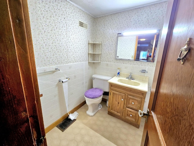 bathroom featuring tile patterned floors, vanity, tile walls, and toilet