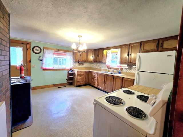 kitchen featuring a chandelier, a textured ceiling, white appliances, and decorative light fixtures