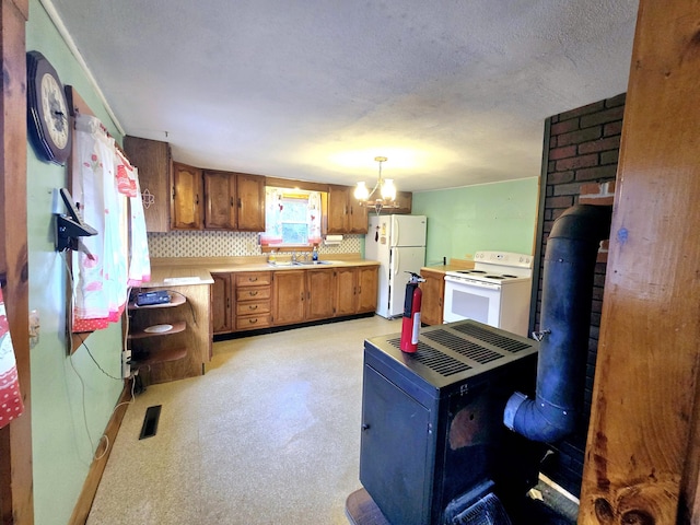 kitchen featuring a wood stove, white appliances, an inviting chandelier, sink, and decorative light fixtures