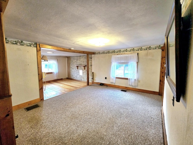 spare room with light carpet, a fireplace, and a textured ceiling