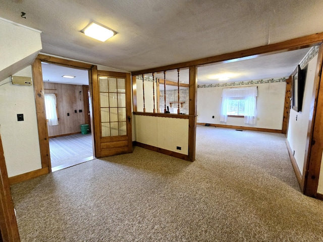 unfurnished room featuring carpet, french doors, a textured ceiling, and wood walls