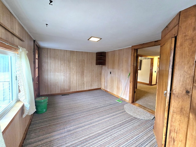 carpeted empty room with wooden walls