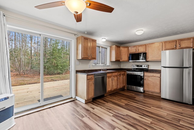 kitchen with dark hardwood / wood-style flooring, stainless steel appliances, heating unit, ceiling fan, and sink