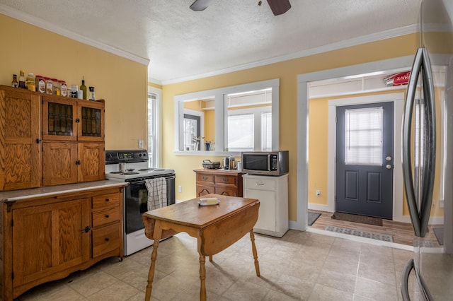 kitchen featuring ceiling fan, appliances with stainless steel finishes, a textured ceiling, light tile patterned floors, and ornamental molding