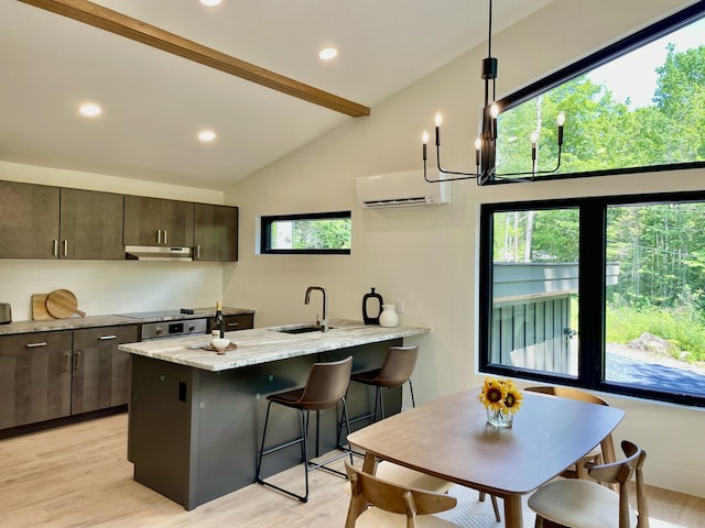 kitchen with light stone counters, light wood-type flooring, an AC wall unit, and sink