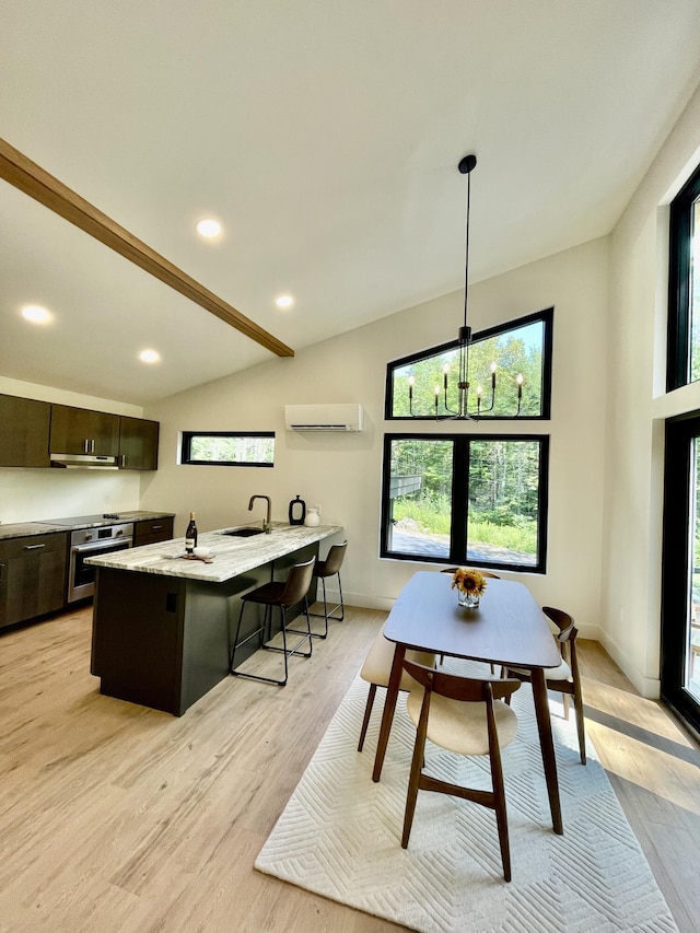 dining space with light wood-type flooring, a wall unit AC, sink, a chandelier, and lofted ceiling