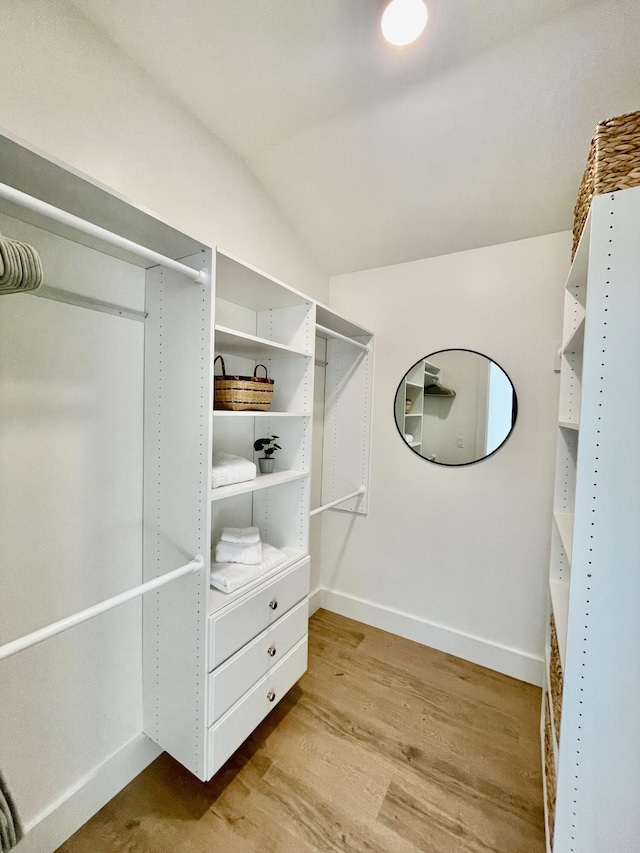 spacious closet featuring light hardwood / wood-style floors and vaulted ceiling