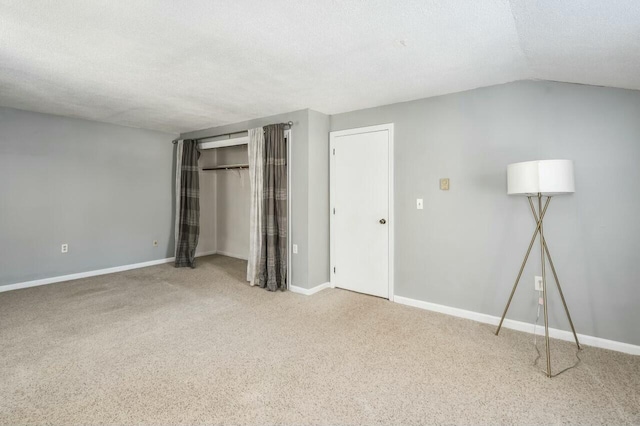 unfurnished bedroom featuring a textured ceiling, carpet flooring, and lofted ceiling