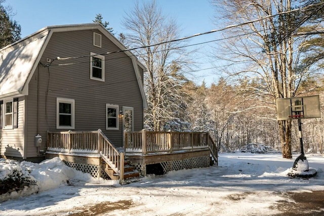 snow covered house featuring a wooden deck