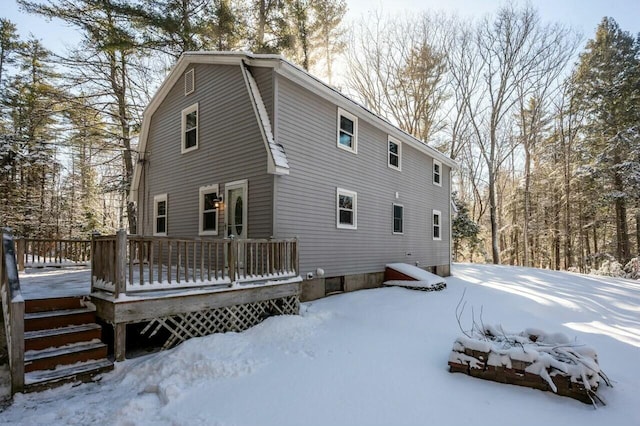 snow covered rear of property with a wooden deck