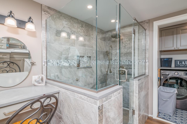 bathroom with washer / dryer, a shower with shower door, and hardwood / wood-style floors