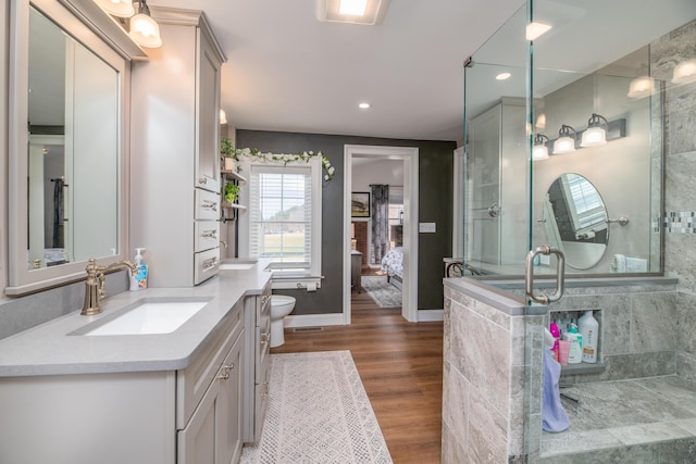 bathroom with toilet, wood-type flooring, vanity, and an enclosed shower