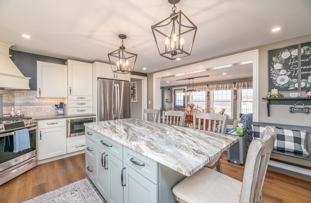 kitchen with pendant lighting, a center island, appliances with stainless steel finishes, a breakfast bar area, and white cabinets