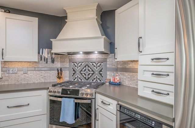 kitchen with decorative backsplash, premium range hood, white cabinets, and appliances with stainless steel finishes