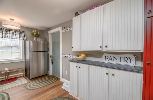 kitchen with light hardwood / wood-style floors, white cabinetry, and stainless steel fridge