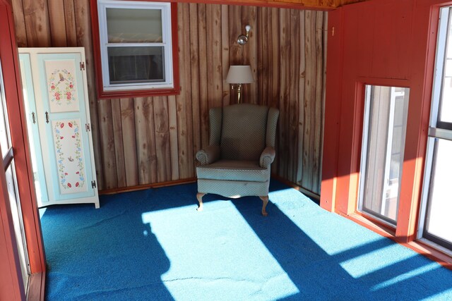 living area featuring carpet flooring and wooden walls