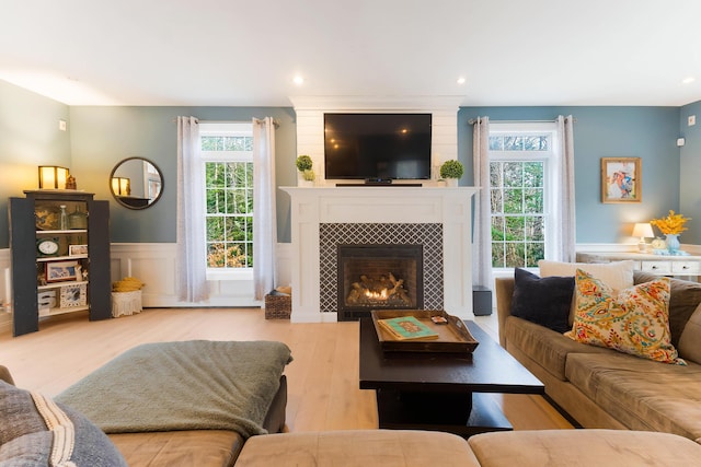 living room with light hardwood / wood-style floors, a tile fireplace, and plenty of natural light