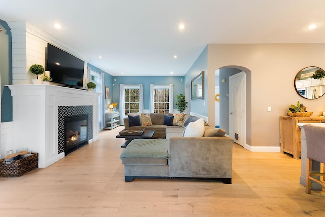 living room featuring a tiled fireplace and light hardwood / wood-style flooring