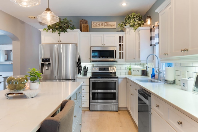 kitchen with sink, white cabinetry, backsplash, pendant lighting, and appliances with stainless steel finishes