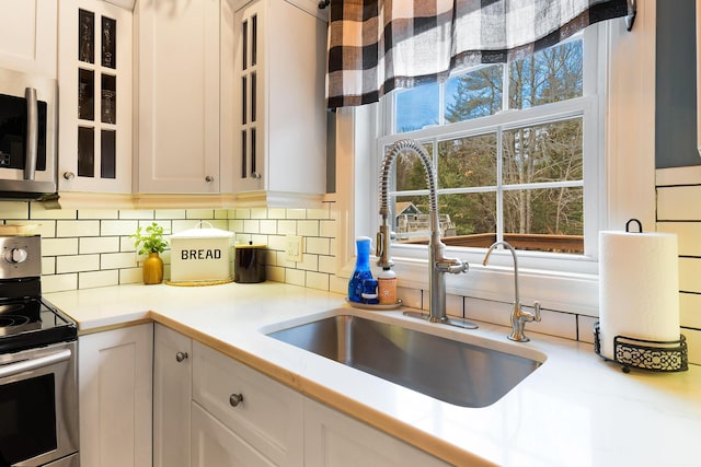 kitchen with white cabinets, stainless steel appliances, decorative backsplash, and sink