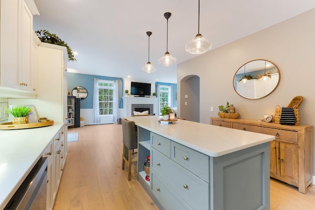 kitchen featuring dishwasher, hanging light fixtures, light wood-type flooring, a center island, and white cabinetry