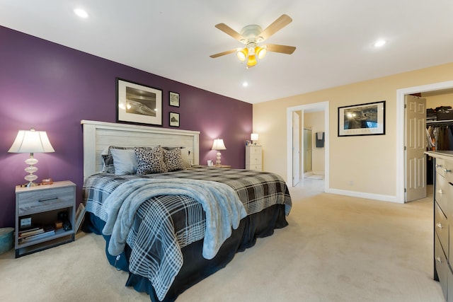 carpeted bedroom with connected bathroom, ceiling fan, and a walk in closet