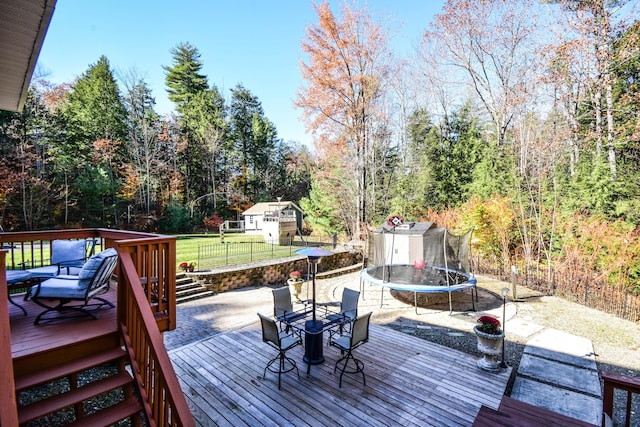 wooden terrace with a yard and a trampoline