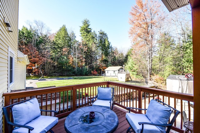 deck with an outdoor fire pit, a storage unit, and a lawn