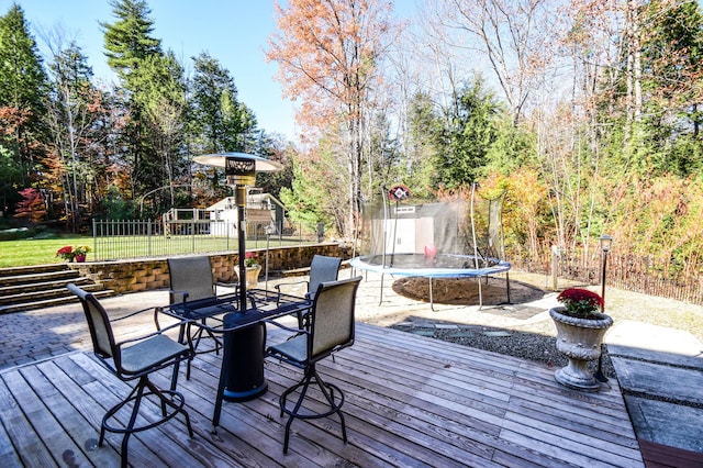 wooden deck featuring a lawn, a playground, and a trampoline