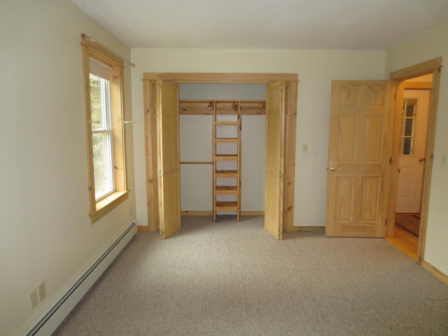 unfurnished bedroom with baseboard heating, light carpet, and a closet